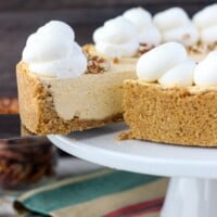a white cake plate with a slice pumpkin cheesecake, and a slice being removed with a spatula