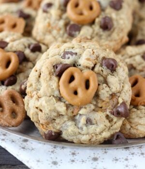 Salty oatmeal cookies with a ribbon of caramel, chopped pretzels, chocolate chips and a salted caramel coated pretzel on top.