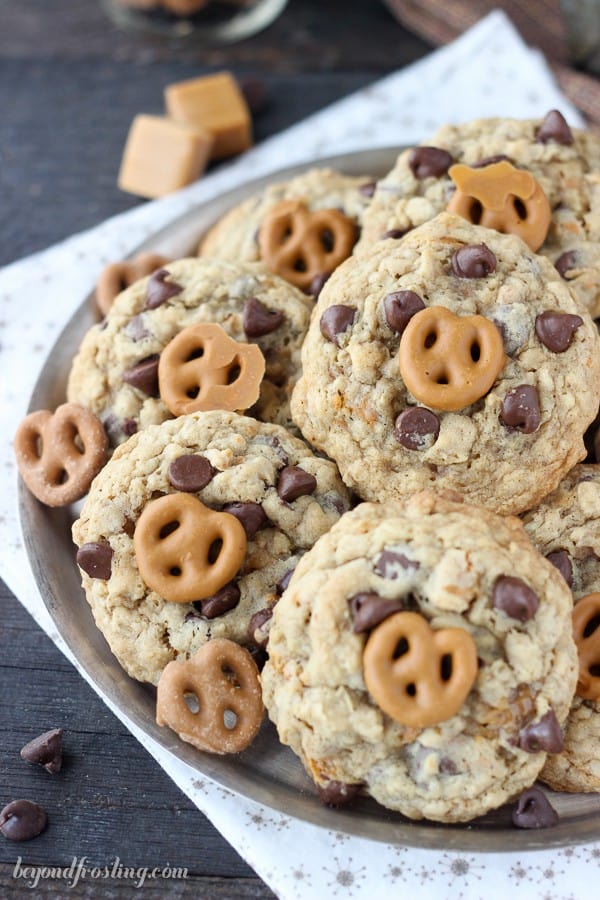 Salty oatmeal cookies with a ribbon of caramel, chopped pretzels, chocolate chips and a salted caramel coated pretzel on top.
