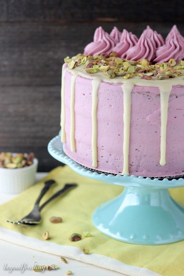 This Blueberry Pistachio Layer cake is a white cake layered with a fresh blueberry frosting and covered with white chocolate ganache and pistachios.