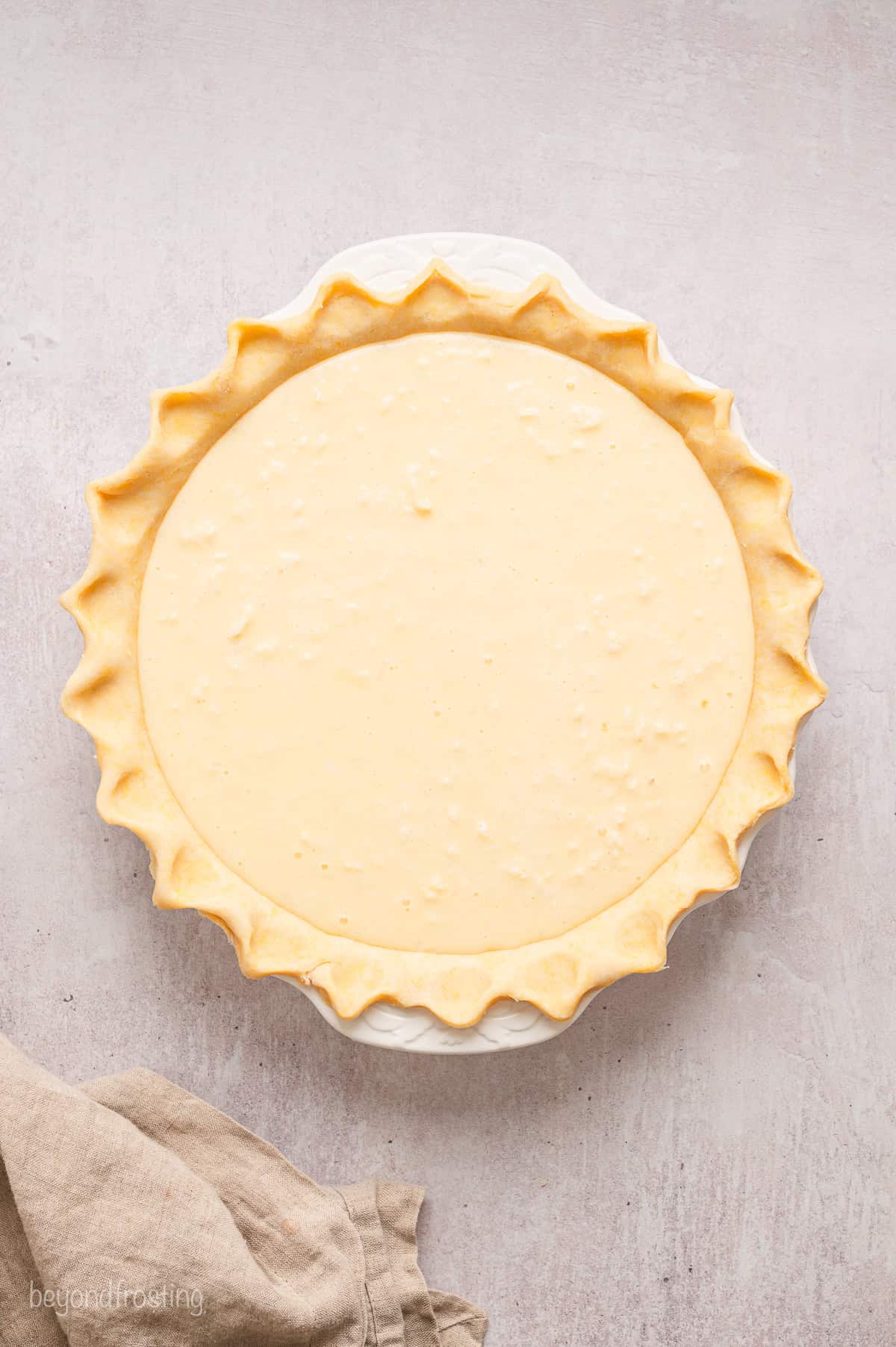 Overhead view of a pie shell filled with coconut custard pie filling.