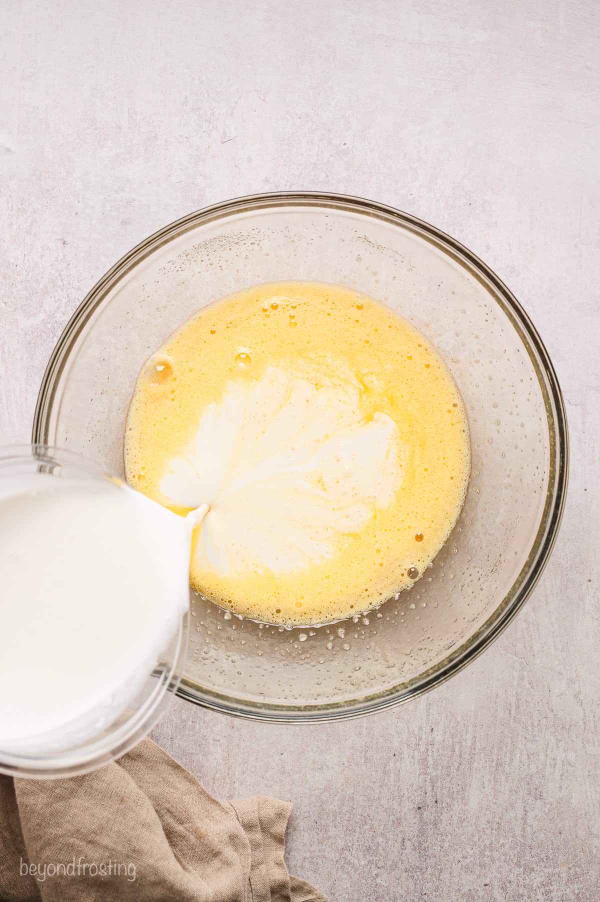 Milk being poured into the wet ingredients for the coconut custard.