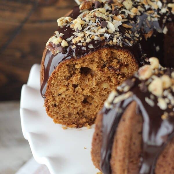 This Pumpkin Seven Layer Bundt Cake is cut so you can see the moist, dense inside. This cake is stuffed with walnuts and chocolate chips and finished with a decadent chocolate ganache and shredded coconut. It’s inspired by my favorite seven layer bars, but with pumpkin!