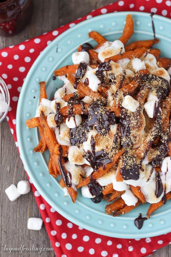 Grab a fork and dig into these Ooey Gooey Sweet Potato S'mores Fries. Layers of crispy sweet potato fries & melted marshmallow drizzled with chocolate and crushed graham crackers.