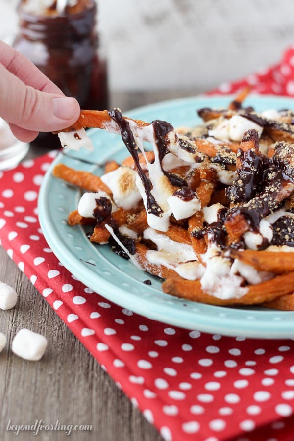 Grab a fork and dig into these Ooey Gooey Sweet Potato S'mores Fries. Layers of crispy sweet potato fries & melted marshmallow drizzled with chocolate and crushed graham crackers.