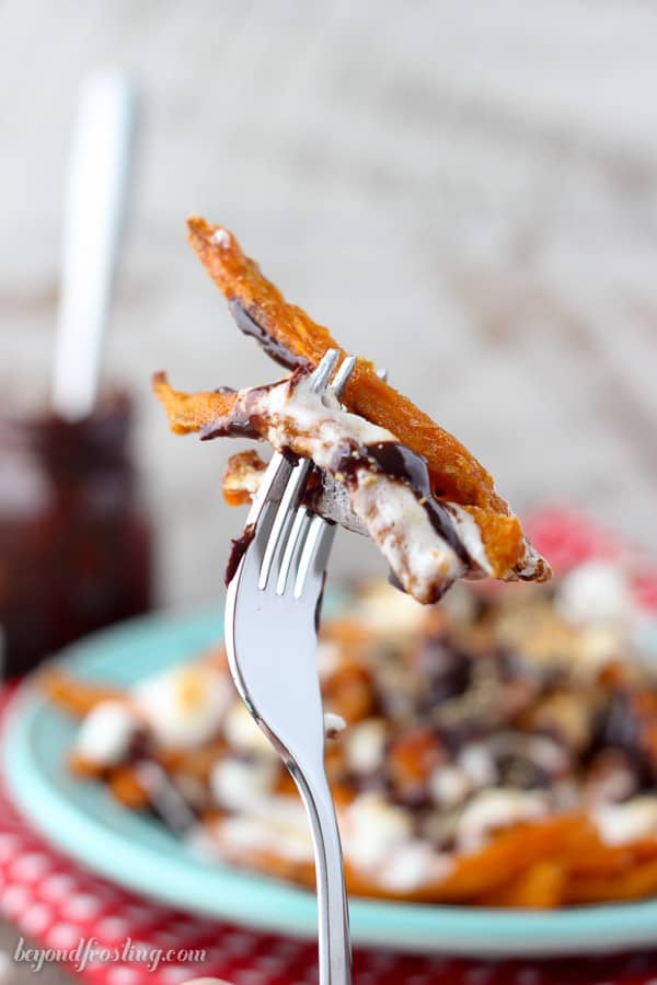 Grab a fork and dig into these Ooey Gooey Sweet Potato S'mores Fries. Layers of crispy sweet potato fries & melted marshmallow drizzled with chocolate and crushed graham crackers.