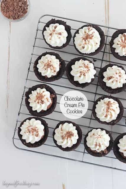 Chocolate Cream Pie Cookie Cups on a wire rack topped with whipped cream and chocolate shavings