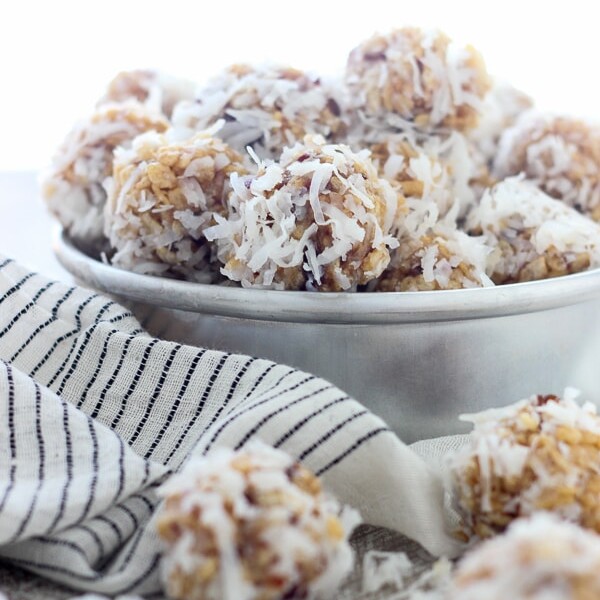 A vintage baking tray filled with coconut balls, and a few scattered on a wooden plank