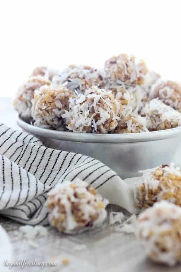 A vintage baking tray filled with coconut balls, and a few scattered on a wooden plank