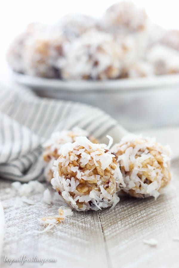 3 coconut balls sitting on a piece of wood with a napkin draped in the background