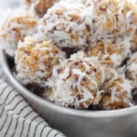 A bowl of coconut date balls nestled on top of a striped dishcloth.