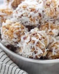 A bowl of coconut date balls nestled on top of a striped dishcloth.