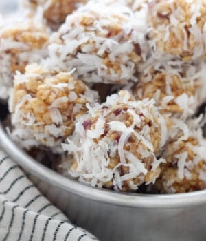 A bowl of coconut date balls nestled on top of a striped dishcloth.