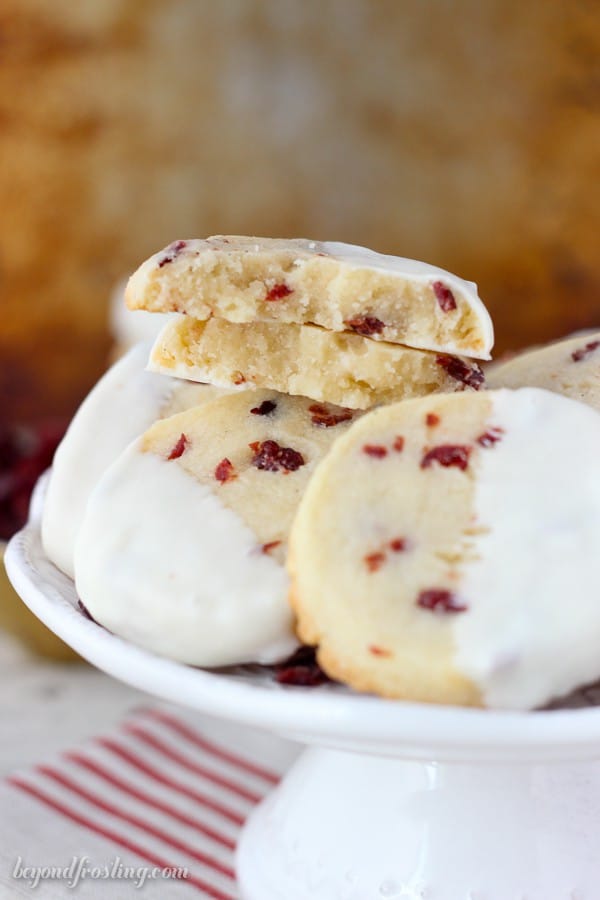 a small white cake stand with dipped shortbread cookies, one cookie split in half to show the center