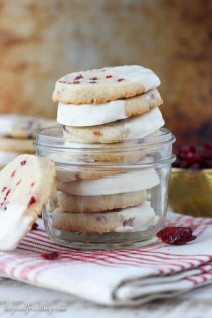 These Cranberry Almond Shortbread Cookies are a soft and buttery almond shortbread loaded with sweetened cranberries and dipped in white chocolate. They are stacked in a small jar.