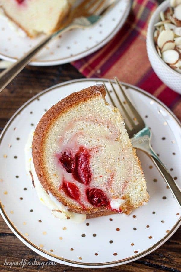 A slice of Cherry Almond Bundt Cake filled with cherry pie filling and topped with a cream cheese glaze on a plate.