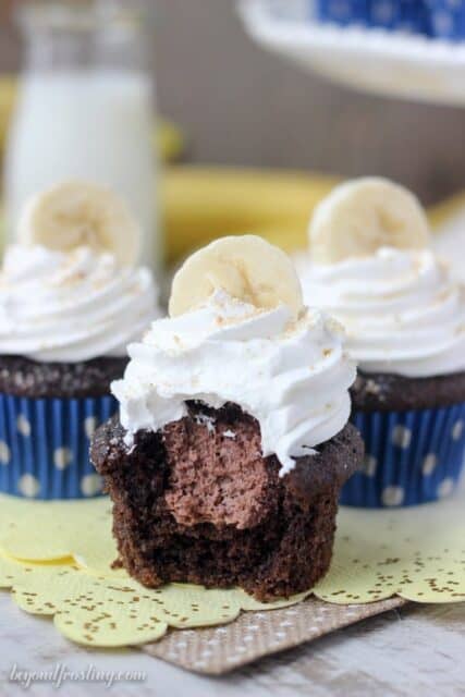 Three chocolate banana cream pie cupcakes: chocolate banana cupcakes filled with a chocolate mousse and topped with whipped cream, bananas and Nilla Wafers.
