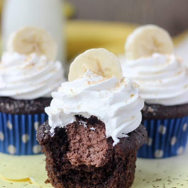 Three chocolate banana cream pie cupcakes: chocolate banana cupcakes filled with a chocolate mousse and topped with whipped cream, bananas and Nilla Wafers.