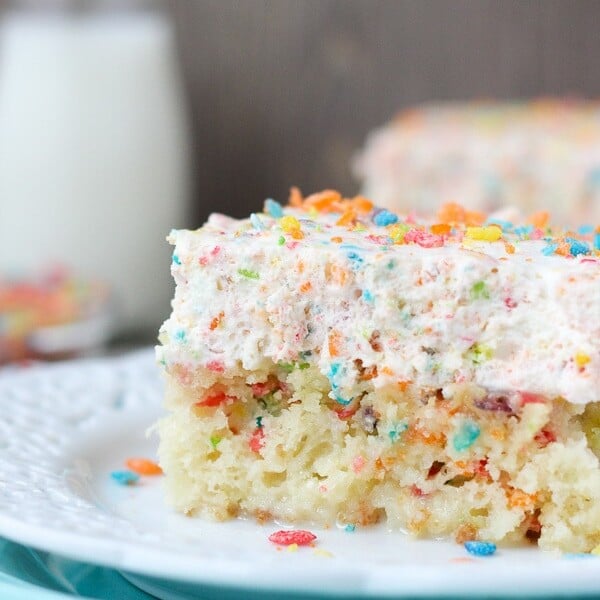 A Slice of Fruity Pebble Poke Cake on a White Plate