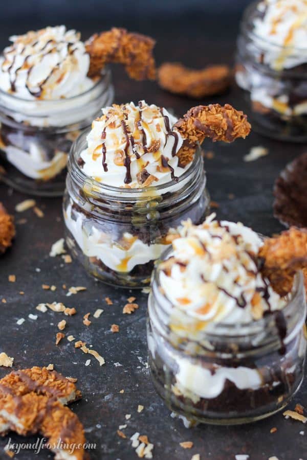 These Samoa Cupcake Shooters have never looked so mouthwatering. Layers of chocolate cake, coconut Swiss meringue buttercream, toasted coconut, chocolate sauce and caramel. Layer after layer of goodness here, topped with a Samoa cookie.