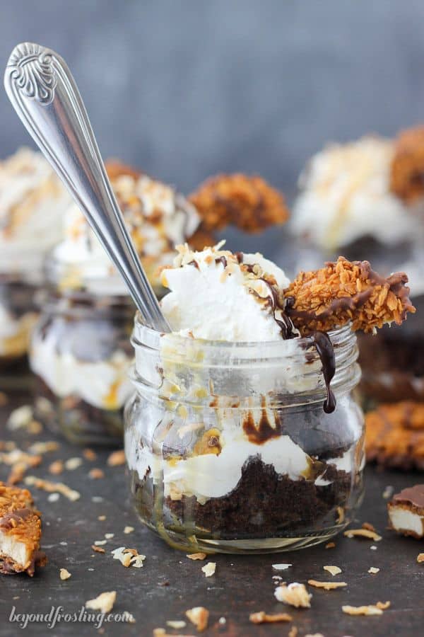 These Samoa Cupcake Shooters have never looked so mouthwatering. Layers of chocolate cake, coconut Swiss meringue buttercream, toasted coconut, chocolate sauce and caramel. Layer after layer of goodness here, topped with a Samoa cookie.