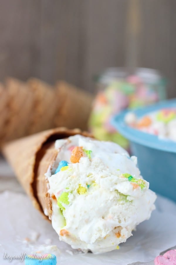 A scoop of Lucky Charms Marshmallow Ice Cream in a cone laying on a table