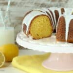 Easy Lemon Bundt Cake topped with Lemon-Vanilla Glaze on a platter with a slice removed.