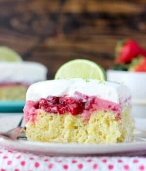 A slice of margarita lime cake topped with a strawberry cream and whipped cream