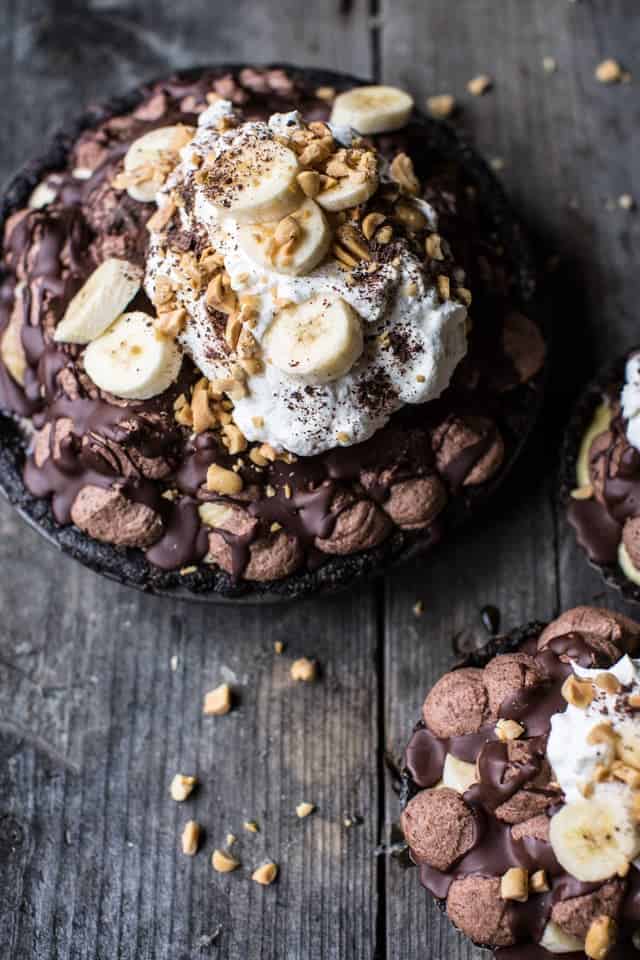 Three Banana Cream Pies with Chocolate and Peanuts on a Wooden Table