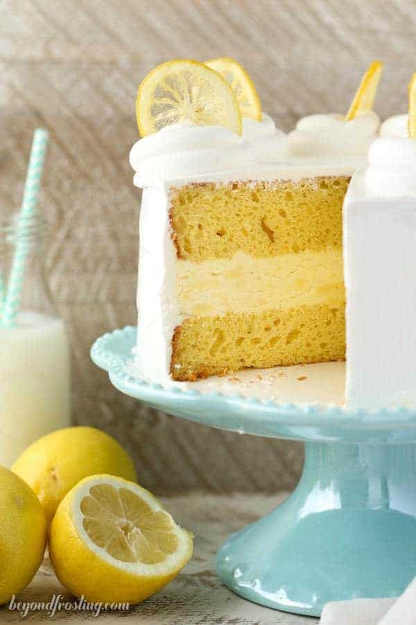 This layered Lemon Ice Cream Cake features two layers of lemon cake with a no-churn lemon ice cream layer sandwiched between them. It's covered in whipped cream and garnished with candied lemons.