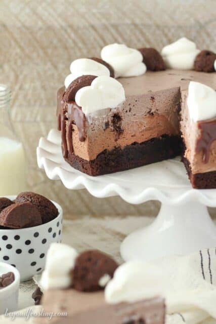 Triple Chocolate Brownie Mousse Cake with a slice missing on a white platter