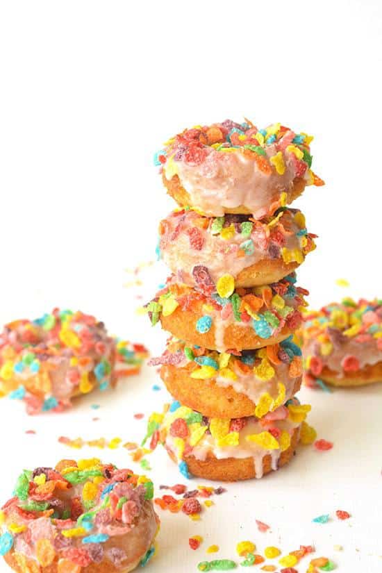 A Tall Stack of Fruity Pebble Cereal Baked Donuts Next to Three Loose Donuts