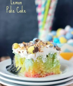 A slice of Tie Dye Coconut Lemon Poke Cake topped with an airy coconut whipped cream, shredded coconut, and crushed Cadbury eggs.