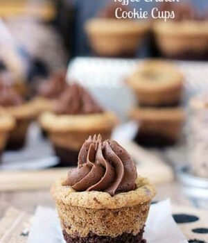 A Brownie Brittle Toffee Crunch Cookie Cup topped with a silky chocolate brownie frosting on a white plate.