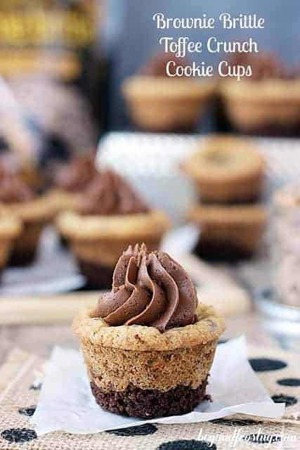 A Brownie Brittle Toffee Crunch Cookie Cup topped with a silky chocolate brownie frosting on a white plate.