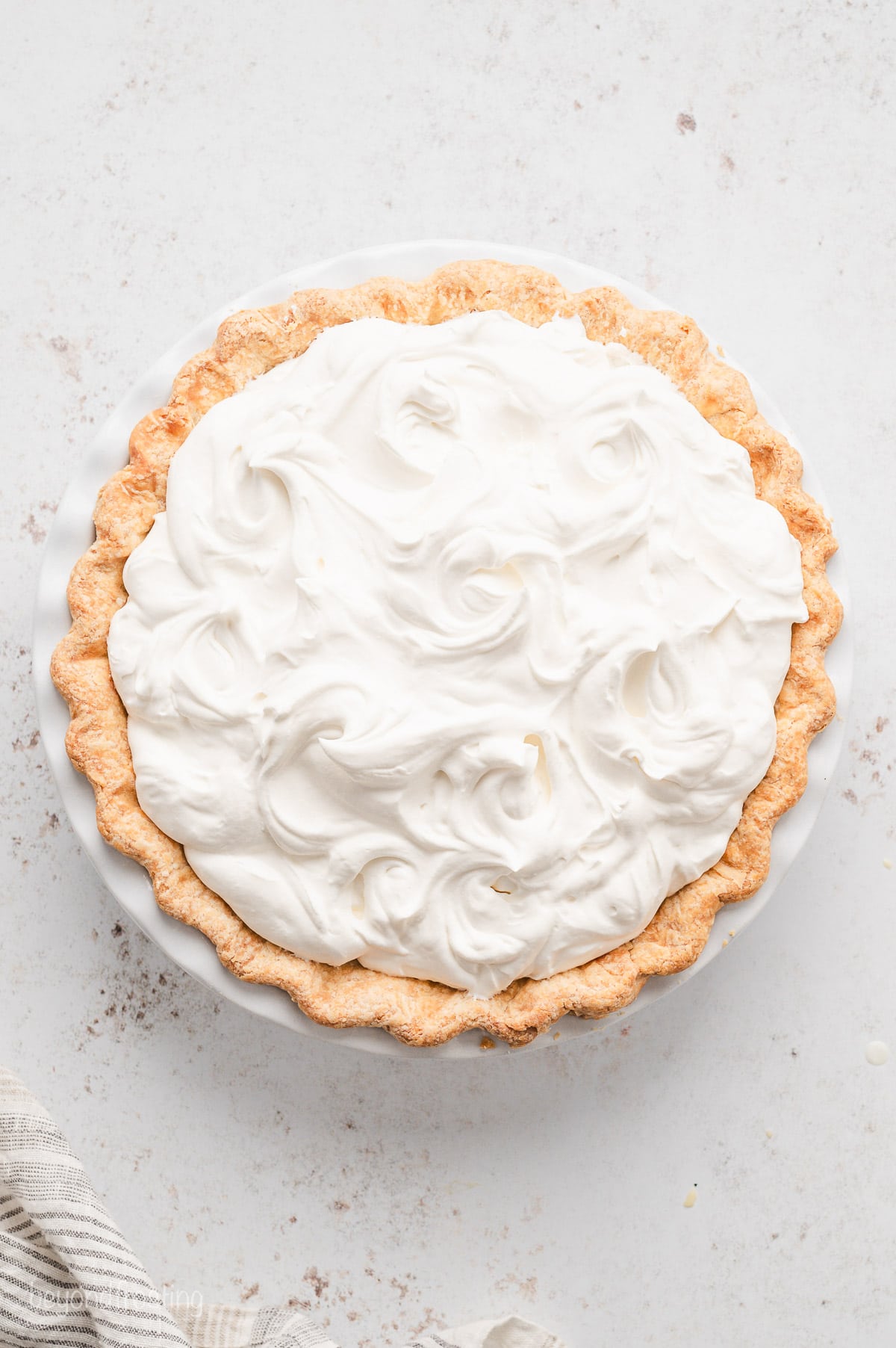 Coconut cream pie topped with whipped cream.