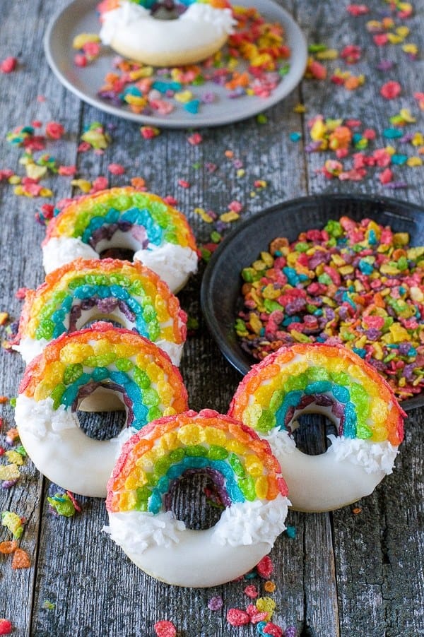 Five Rainbow Donuts Next to a Bowl of Fruity Pebbles