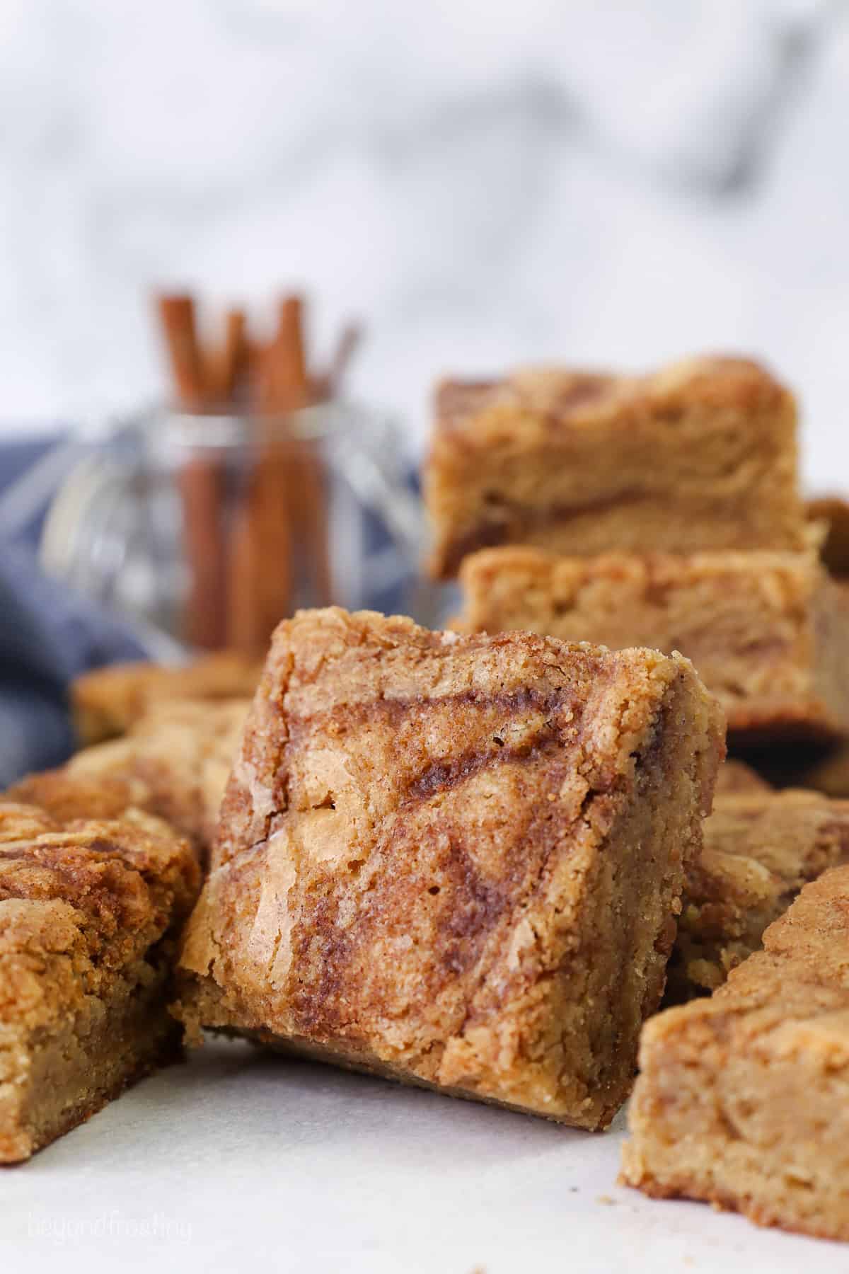Side view of assorted cinnamon roll blondies stacked next to one another on a countertop.