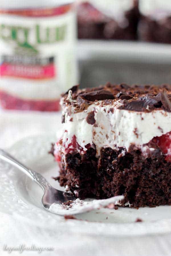 This Black Forest Poke Cake is a gooey chocolate cake filled with hot fudge and cherry pie filling. It is topped with fresh whipped cream and chocolate shavings.