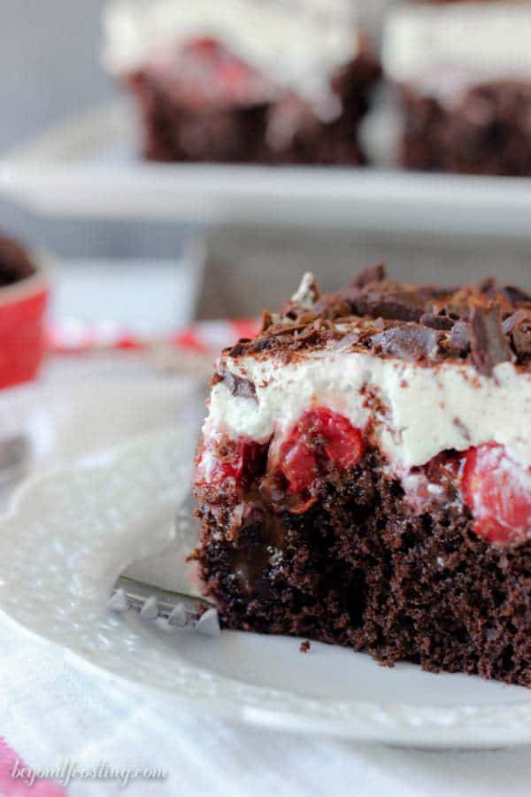 This Black Forest Poke Cake is a gooey chocolate cake filled with hot fudge and cherry pie filling. It is topped with fresh whipped cream and chocolate shavings.