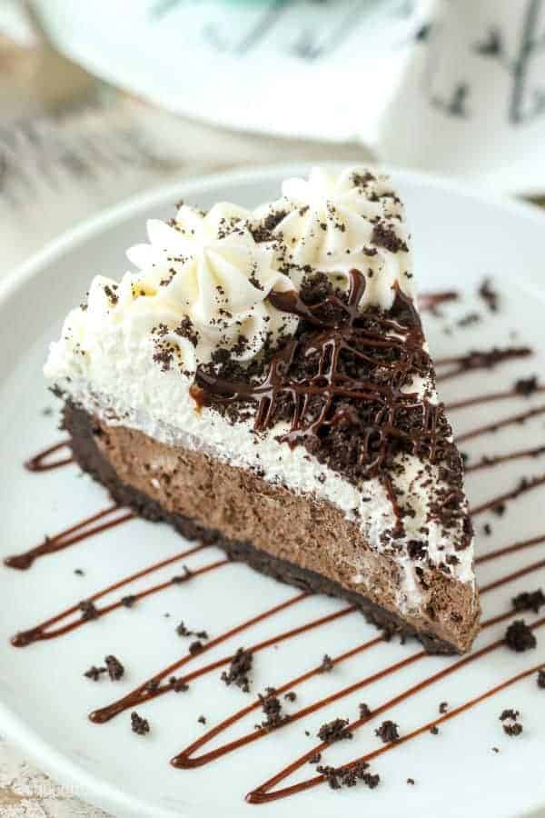A slice of no-bake chocolate marshmallow pie on a plate drizzled with chocolate fudge.