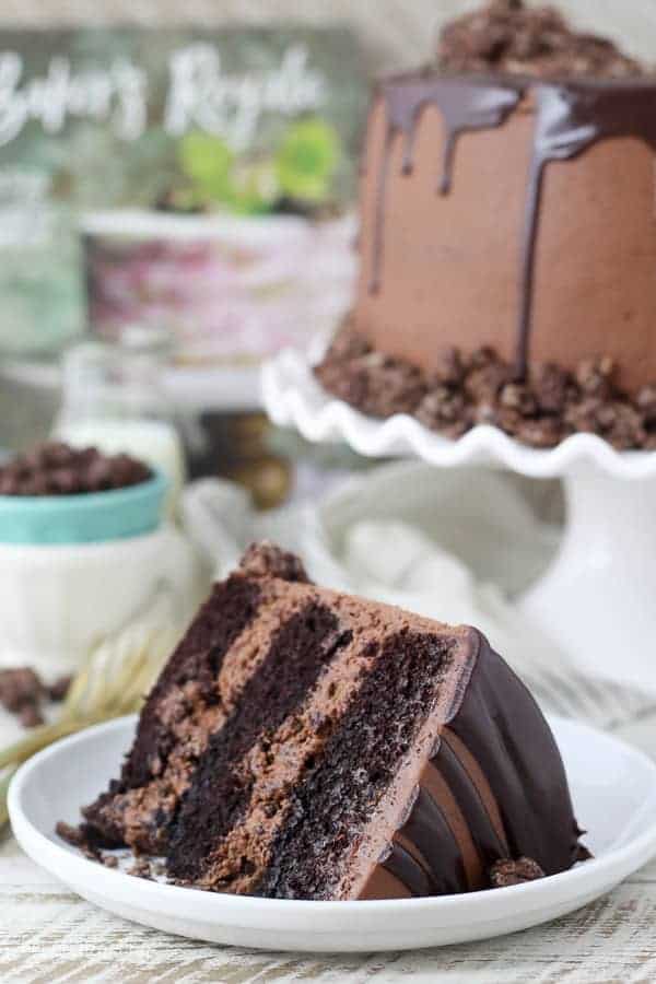 A gorgeous slice of chocolate cake with a swirled chocolate frosting, the whole cake is blurred out in the background
