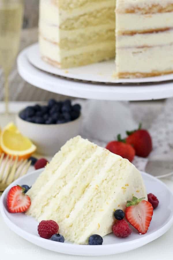 A gorgeous slice of cake on a white plate with berries on it