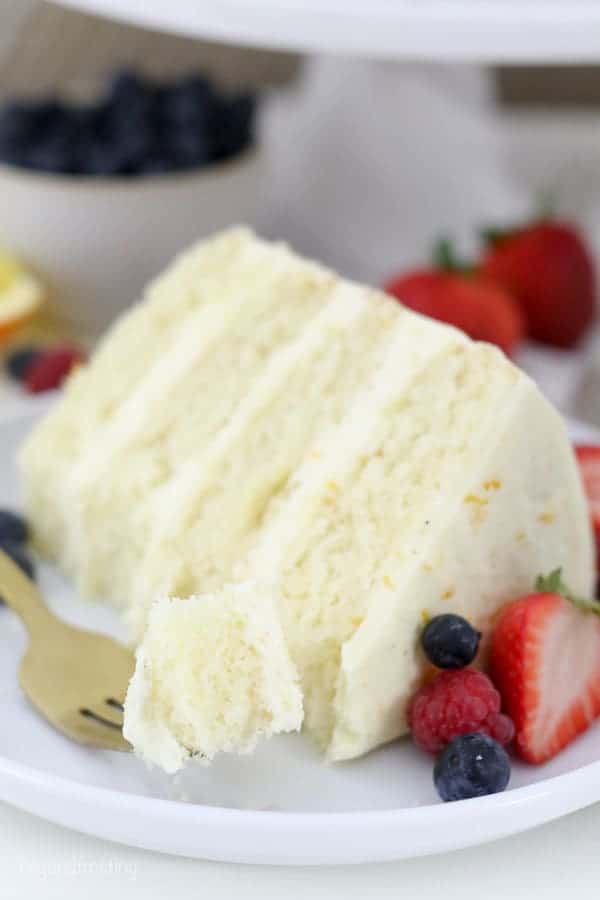 A slice of cake with berries, and a gold fork with a bite of cake on it