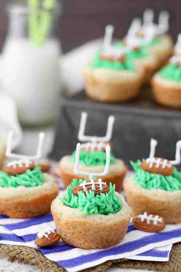 cookie cups filled with green frosting that looks like grass with a football shaped almond and a candy field goal