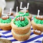 cookie cups filled with green frosting that looks like grass with a football shaped almond and a candy field goal