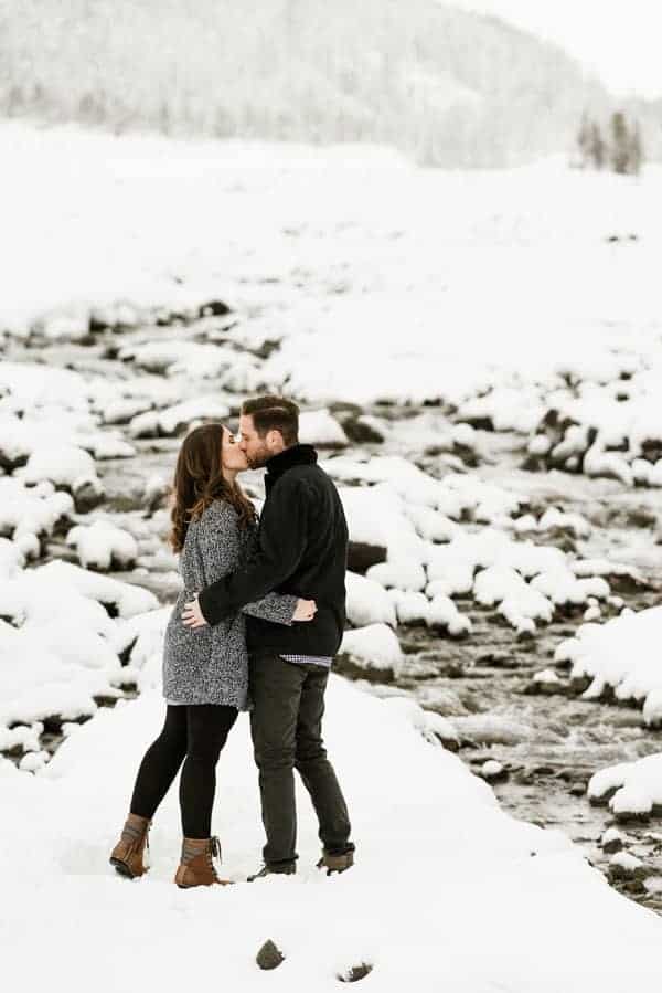 a couple kissing with a mountain backdrop