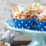 Easter themed cupcakes that look like a bird nest with chocolate eggs in the middle sitting on a teal cake plate.