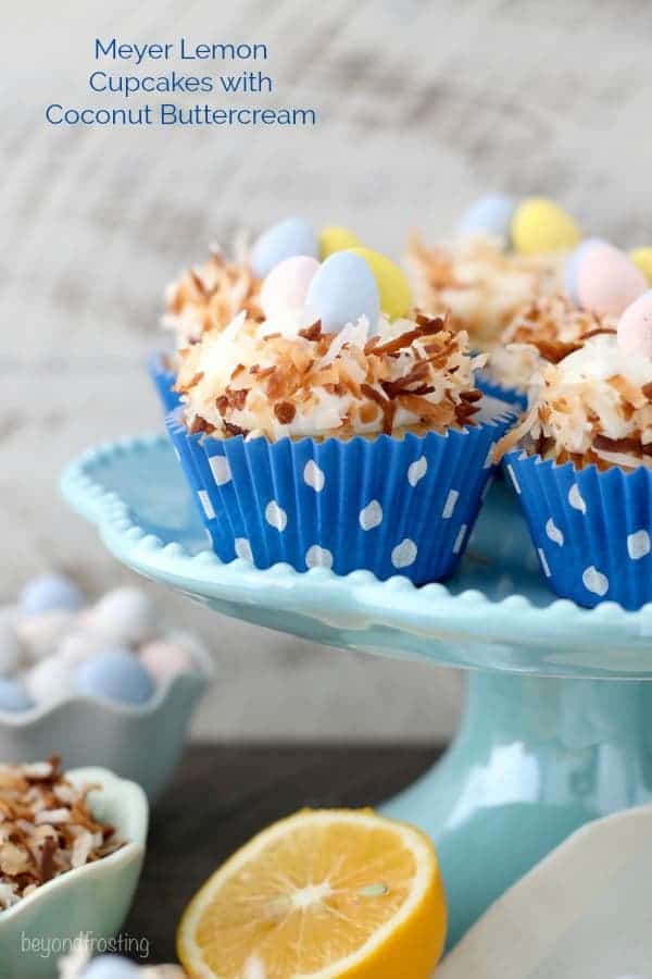 Easter themed Meyer Lemon cupcakes that look like a bird nest with chocolate eggs in the middle sitting on a teal cake plate.