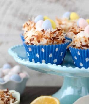 Easter themed cupcakes that look like a bird nest with chocolate eggs in the middle sitting on a teal cake plate.